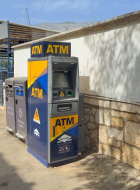 Korcula, Hırvatistan - 30 Haziran 2024: Euronet ATM makinesi sokakta, yanında iki çöp tenekesi var. 