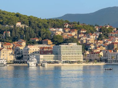 Split, Hırvatistan - 1 Temmuz 2024: Batı Şeria kıyısındaki Boardwalk ve Trumbiceva obala caddeleri arasında yeni inşa edilen Beyaz Lüks Otel Büyükelçisi, yeşil parka yanaşan tekneler ve şehir manzarası