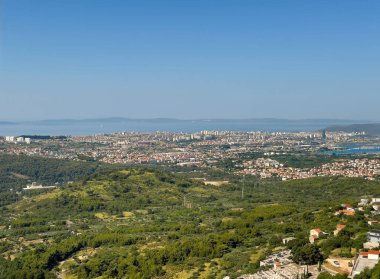Split, Hırvatistan - 1 Temmuz 2024: Klis Kalesi. Şehir merkezine bakan Adriyatik Denizi 'nin arkasında mavi gökyüzünün altında yeşil ağaçlar var.