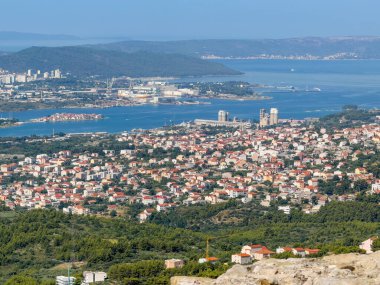 Split, Croatia - July 1, 2024: Looking down from Klis Fortress to far reaching Adriatic bay, we see port installations and the large Cemex cement factory up front surrounded by white houses with red roofs clipart