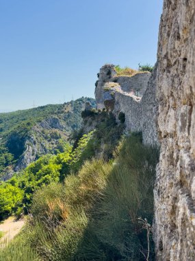 Split, Hırvatistan - 1 Temmuz 2024: Klis Kalesi. Surların dış duvarlarına tekrar tekrar bakıyorum. Kayalık yüzeyde yeşil bitki örtüsü ve mavi gökyüzü