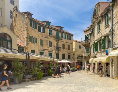 Split, Hırvatistan - 1 Temmuz 2024: Şehir merkezi tarihi. Radikal Kardeşler Meydanı batıda her iki uzun üçgende de restoranlar ve perakende mağazaları var. Ticari işletmelerin üzerinde eski konutlar var. Yayalar hazır.