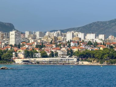 Split, Hırvatistan - 1 Temmuz 2024: Uvala Bacvice 'nin doğu yakası, koy adı verilen küçük bir mağara. Turizmle ilgili uzun binalarla dolu bir sahil. Arka taraftaki büyük apartman manzarası. 
