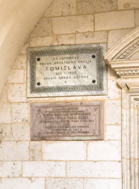 Kotor, Karadağ - 2 Temmuz 2024: Eski tarihi şehir merkezi. Aziz Tryphon Katedral plaketleri. Binyıl Çağı 'nın ve bina ve onun azizi hakkındaki diğer ünlü gerçeklerin anısına girişte.