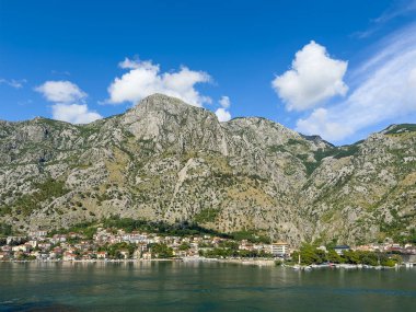 Kotor, Karadağ - 2 Temmuz 2024: Primorac Water Polo spor kulübü ve geniş şehir merkezi, arkasında binalar ve dağ sıraları bulunan manzara, Mavi Bulutlu okul