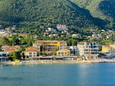Kotor Körfezi, Karadağ - 2 Temmuz 2024: Portonovo şehrinin bir Portonovi plaj kulübü oteli ve tatil köyü var. Arkadaki orman dağı.