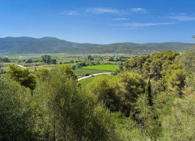 Meospotamos, Yunanistan - 3 Temmuz 2024: Acheron Necromanteion. Mavi gökyüzünün altındaki yeşil tarımsal araziye bakıyorum.