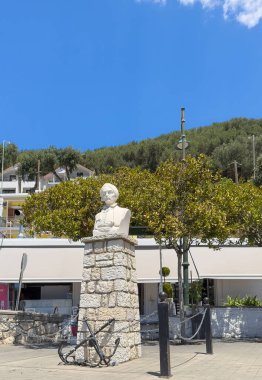 Yunanistan 'ın Parga kenti - 3 Temmuz 2024: Yunan devrimci lider ve siyasetçi Andreas Zaimis, tahta kaldırımda iki çapa ile beyaz taş büstü heykel. Yeşil yapraklar ve mavi gökyüzü