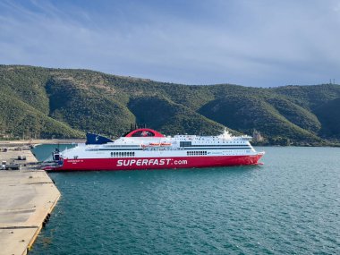 Igoumenitsa, Yunanistan - 3 Temmuz 2024: Liman. Süper hızlı feribot vagonlara ve kamyonlara yükleniyor. Güney sahilinin ormanlık tepeleri arkada.