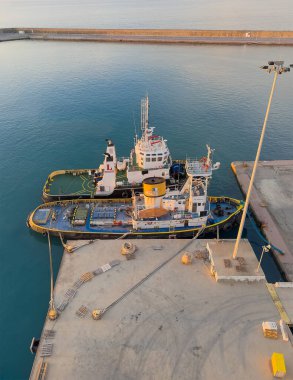 Katakolo, Greece - July 4, 2024: Two docked tugboats in port during sunrise. Long pier in back clipart