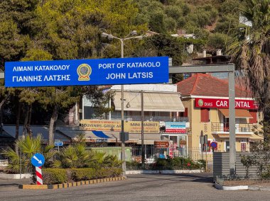 Katakolo, Yunanistan - 4 Temmuz 2024: Limana giriş kapısı John Latsis 'ten sonra isimlendirildi. Hediyelik eşya dükkanı, mini market ve hemen arkasında bir araba kiralama şirketi.