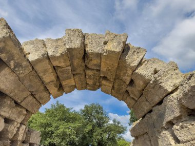 Olympia, Yunanistan - 4 Temmuz 2024: Olimpiyat Oyunlarının doğduğu yer. Stadyuma giden yolun üzerinde antik taş yay var.