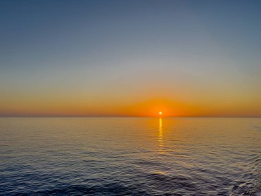 İyon Denizi, Sicilya 'nın doğusu, İtalya - 5 Temmuz 2024: Gündoğumu rengi gökyüzü ve deniz mavisi, ufukta küçük turuncu kuşak