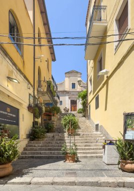 Taormina, Sicilya, İtalya - 5 Temmuz 2024: Corso Umberto 'dan, köşesinde Infinity butiği olan eski El Carmine Kilisesi' ne giden yol.