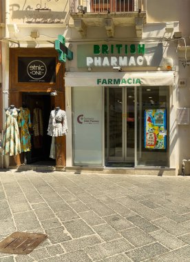 Taormina, Sicilya, İtalya - 5 Temmuz 2024: Corso Umberto 'daki İngiliz Eczanesi, Farmacia. Komşu olarak Etnik Bir elbise mağazası