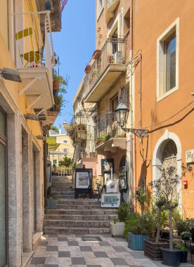Taormina, Sicilya, İtalya - 5 Temmuz 2024: Fretelli Ingegnere üzerinden, Corso Umberto açıklarında bir sanat atölyesi, merdivenleri ve saksıları var. Daire cepheleri