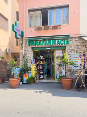 Taormina, Sicilya, İtalya - 5 Temmuz 2024: Eczane, Parafarmacia, Via Luigi Pirandello 'da, ön cephede güneş koruma ürünleri ve reklam tabelaları sergileniyor. Yukarıdaki daire.