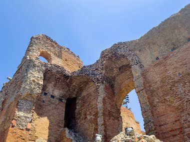 Taormina, Sicilya, İtalya - 5 Temmuz 2024: Sahne arkasından Antik Yunan tiyatrosunun veya mavi gökyüzü altındaki Teatro Antico 'nun NW köşe harabesine bakıyor