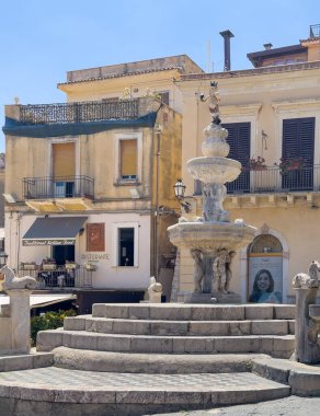 Taormina, Sicilya, İtalya - 5 Temmuz 2024: Piazza Duomo. 4 çeşme olarak adlandırılan barok çeşmesinde yarı insan, yarı at Minotaur var. Dipte daha fazla at. Al Duomo restoranlarından birinin arkasındaki bej cepheler..