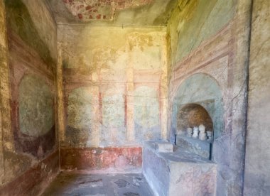 Pompeii, Campania, İtalya - 6 Temmuz 2024: Antik Roma şehri kalıntıları. Casa del Menandro. Köşesinde küçük atalardan kalma sunağı olan bir oda. Eski boyalı duvarların renkleri kaldı