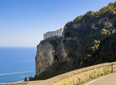 Amalfi, Salerno, İtalya - 6 Temmuz 2024: Monastero Santa Rosa Hotel & Spa uçurumunda, dibi mavi denizle kaplı, SS366 yolundan görülüyor