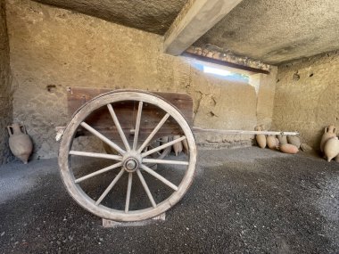 Pompeii, Campania, İtalya - 6 Temmuz 2024: Antik Roma şehri kalıntıları. Casa del Menandro. Malikanenin arkasındaki hizmetçi odalarında küçük bir araba kalıntısı bulduk. Bir de şarap veya su kabı. Köşede bir araya getirilmiş.