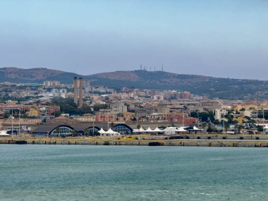 Civitavecchia, İtalya - 7 Temmuz 2024: Limanda otomobil ticareti del Mare feribot terminali arkasında şehir manzarası, endüstriyel geçmişten iki tarihi mimari baca