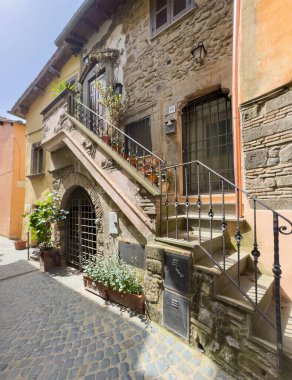 Trevignano Romano, Lazio, İtalya - 7 Temmuz 2024 Via Umberto 22 'de metal korkuluklu güzel bir cephe. Saksılar dolusu bitki ve küçük duvar heykelleri