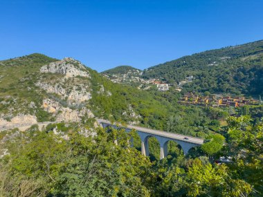 Eze, Fransa - 9 Temmuz 2024: M6007 yolunun batısında yeşil manzaralı beyaz kavis köprüsü