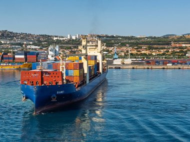 Marsilya, Fransa - 10 Temmuz 2024: Djanet konteyner gemisi limandaki konteyner terminalinden ayrılıyor. Arka planda konut binaları olan manzara