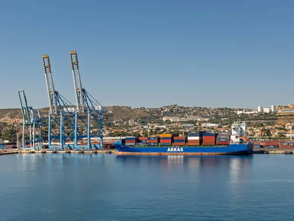 Marsilya, Fransa - 10 Temmuz 2024: ARKAS konteyner gemisi konteyner terminaline yanaştı. Renkli konteynır kutuları, vinçler ve geniş konut ve sanayi binaları yığını