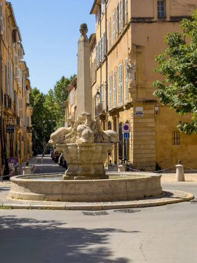 Aix-en-Provence, Fransa - 10 Temmuz 2024: Yunus çeşmesi meydanda, Place des 4 Dauphins, Rue Cardinale ve Rue du 4 Eylül kavşağında. Sarı taş cepheler, Jardin Mazarin restoranlarından biri.