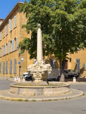 Aix-en-Provence, Fransa - 10 Temmuz 2024: Yunus çeşmesi meydanda, Place des 4 Dauphins, Rue Cardinale ve Rue du 4 Eylül kavşağında. Sarı taş cepheler ve arabalar