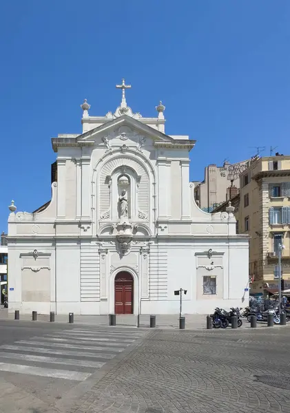 Marsilya, Fransa - 10 Temmuz 2024 şehir merkezi manzarası. Eglise Saint-Ferreol les Augustins mavi gökyüzünün altında eski limanın NE köşesinde beyaz cephe üzerinde aziz heykeli ve motosikletlerle