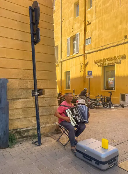 Aix-en-Provence, Fransa - 10 Temmuz 2024: Cr Mirabeau ve Rue du 4 Septembre kavşağında Guerrini Accordion çalan sokak müzisyeni. Banka binası onun tarafında.
