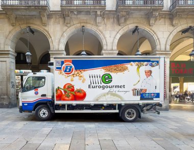 Barselona, İspanya - 11 Temmuz 2024: Barri Gotic, Placa Reial Meydanı. Eurogourmet kamyonu gıda ürünleri dağıtıyor. Domatesler ve resim yapan dost canlısı bir şef. Arkanızda taş kaldırım var.