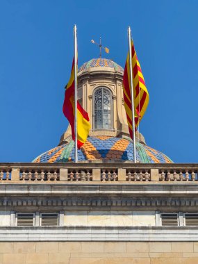 Barcelona, İspanya - 11 Temmuz 2024: Barri Gotic, Palau de la Generalitat de Catalunya 'nın ya da Katalonya Hükümeti Sarayı' nın tepesinde Sant Jaume Meydanı, plaka, mavi gökyüzü altında bayraklar. 