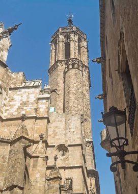 Barcelona, İspanya - 11 Temmuz 2024: Barri Gotic, On Placa de Sant Iu, Carrer dels Comptes tarafından görülen Katedral 'in yan kulesi. Duvarın üstünde fener ve heykeller var.