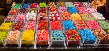 Barselona, İspanya - 11 Temmuz 2024: Mercat de la Boqueria, pazarı kapsıyordu. Renkli şeker sepetleri, yenmeye hazır, sergileniyor