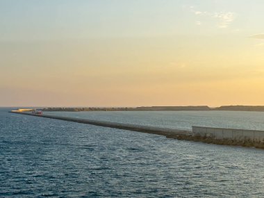 Barselona, İspanya - 11 Temmuz 2024: Limanın güney kısmında, gün batımında açık denizden görülen koruyucu bariyer. Kırmızı iskele onarım ve teftiş gemisi
