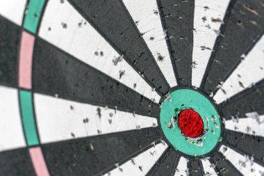 In a lively pub atmosphere, a close-up of a well-used dartboard displays its worn surface and vibrant colors, capturing the excitement of an evening darts game among friends.