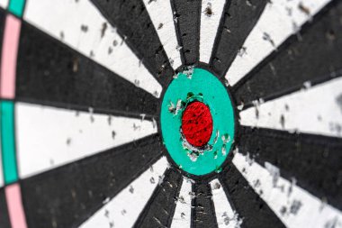 Close-up of a dartboard highlighting the central bullseye marked in red, surrounded by black and white sections, depicting signs of frequent use.