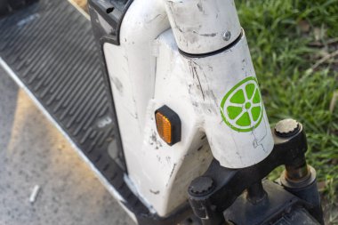 Budapeşte, Macaristan - 21 Mart 2025 Lime elektrikli scooter 'ın parçaları sergilenmektedir. Güneş ışığı scooter 'ı aydınlatır, aşınmasını vurgular ve çimenlik zemine vurgu yapar.