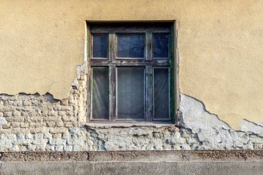 Yıpranmış ahşap bir pencere, eski bir binanın çatlak ve soyulmuş duvarında zamanın akışını gözler önüne seriyor. Çevreleyen dokular kentsel bozulmanın zengin bir görsel öyküsünü yaratıyor..