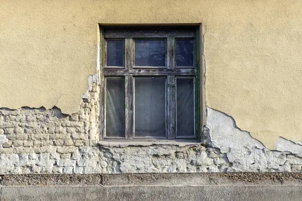 Yıpranmış ahşap bir pencere, eski bir binanın çatlak ve soyulmuş duvarında zamanın akışını gözler önüne seriyor. Çevreleyen dokular kentsel bozulmanın zengin bir görsel öyküsünü yaratıyor..