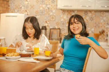 Two sisters having on breakfast at the kitchen.