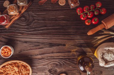 Top view of table with chicken, cheddar cheese, ingredients and space to pizza application.