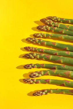 Yeşil, taze kuşkonmaz ve parlak sarı kağıtta koyu gölgeler. Sağlıklı organik gıda ve diyet konsepti. Ulusal Kuşkonmaz Günü