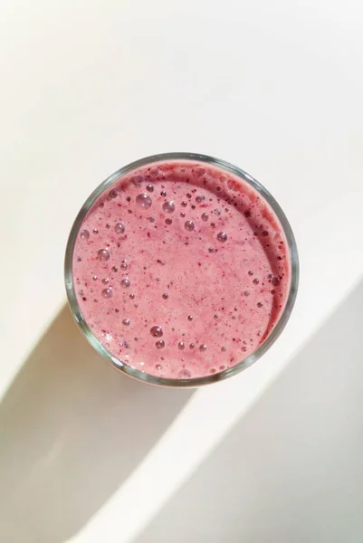 蓝莓在透明的玻璃杯中 在明亮的背景下 有着长长的阴影 顶部的景色 健康早餐 — 图库照片
