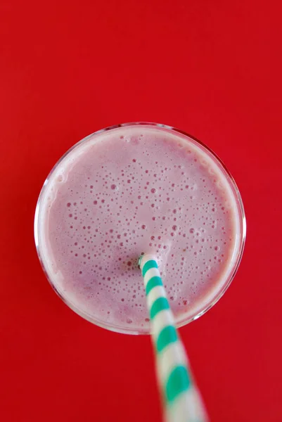 赤い背景の透明なガラスの中にストロベリーとバナナピンクのスムージー トップビュー ミルクシェイク 健康的な朝食 — ストック写真